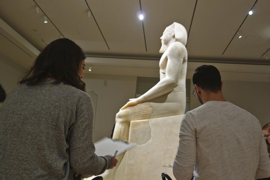 Students observing a museum sculpture